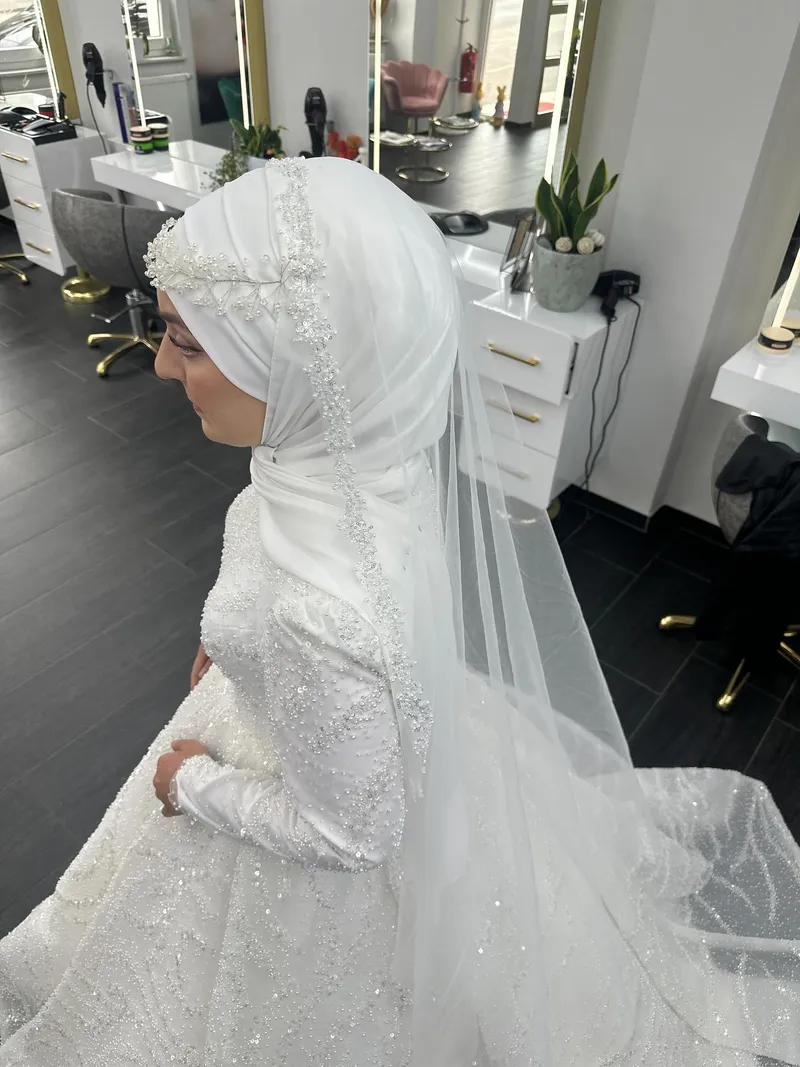 Hijab-Brautstyling mit weißem Schleier und Perlenbesatz im Salon