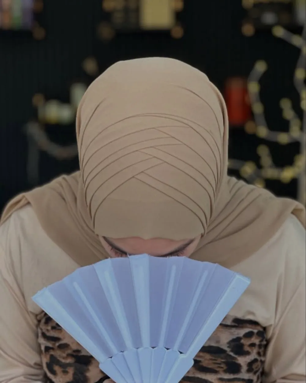 Beiger Hijab mit feiner Drapierung und Fächer, dezentes Styling im Salon